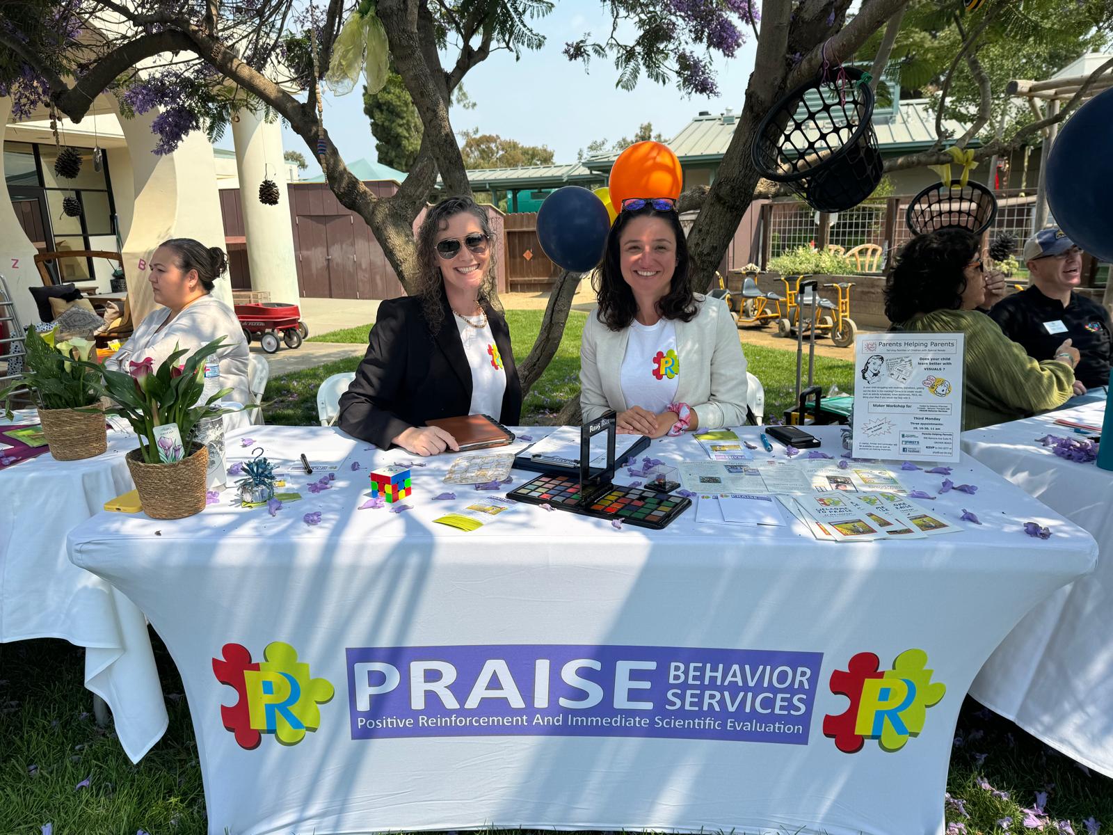 Praise Behavior table at a community event with two women sitting at the table